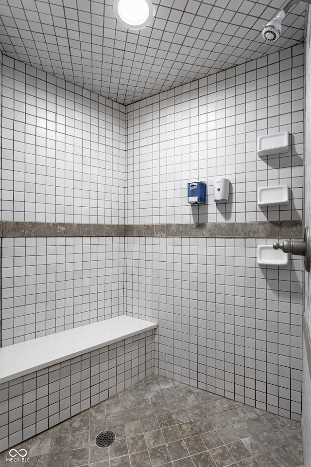 bathroom with tiled shower and tile walls
