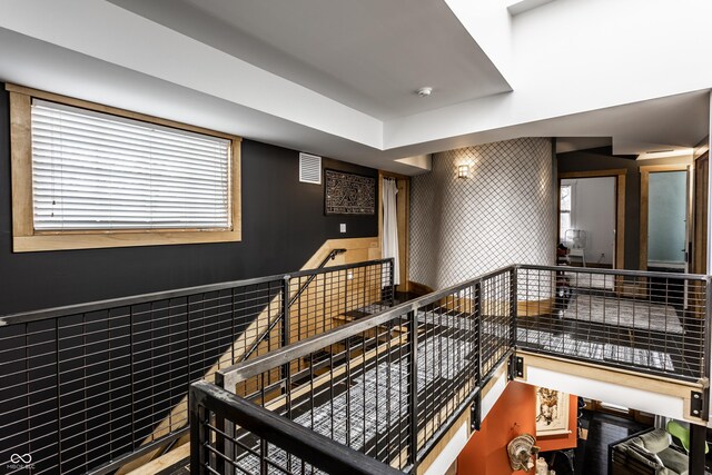 stairs with a wainscoted wall, tile walls, and visible vents