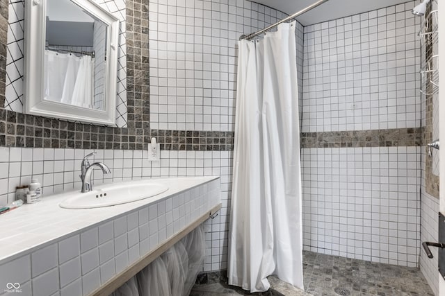 bathroom with a tile shower, decorative backsplash, tile walls, and vanity
