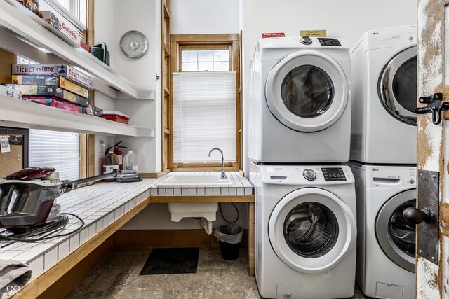 laundry room with laundry area, stacked washer / dryer, and a sink