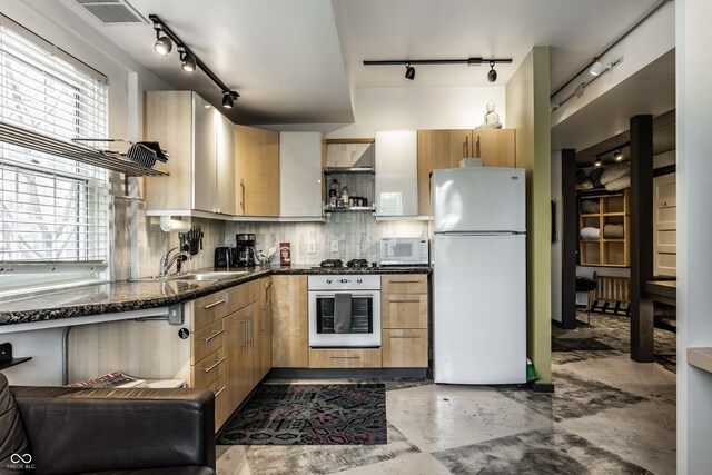 kitchen with visible vents, backsplash, a healthy amount of sunlight, white appliances, and a sink