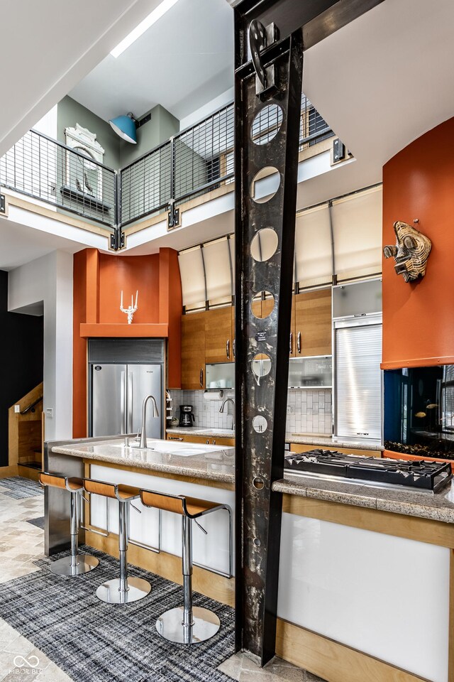 kitchen featuring a high ceiling, backsplash, and stainless steel refrigerator