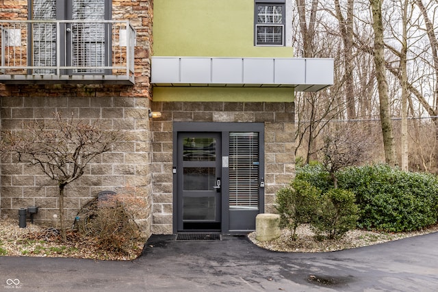 property entrance featuring stucco siding and stone siding