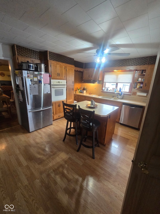 kitchen with a breakfast bar area, light countertops, appliances with stainless steel finishes, light wood-style floors, and a kitchen island