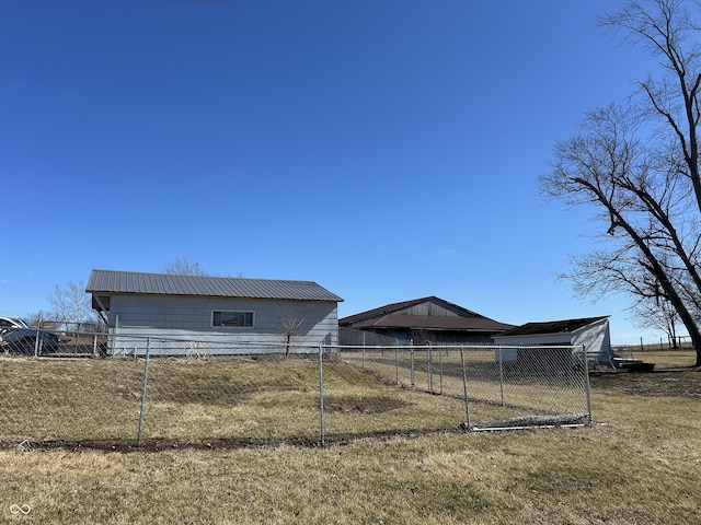 exterior space with metal roof, fence, and a lawn