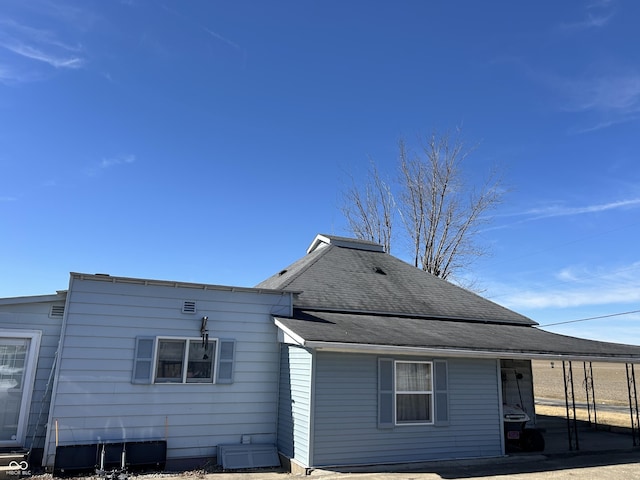 rear view of property with central AC and roof with shingles