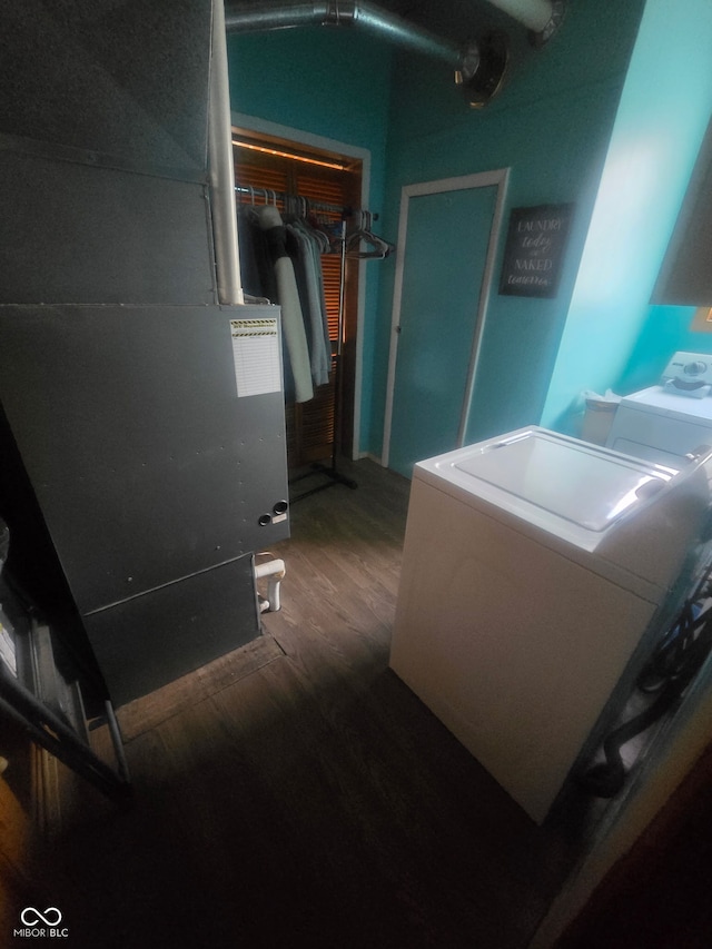 clothes washing area featuring laundry area, heating unit, wood finished floors, and washer and dryer