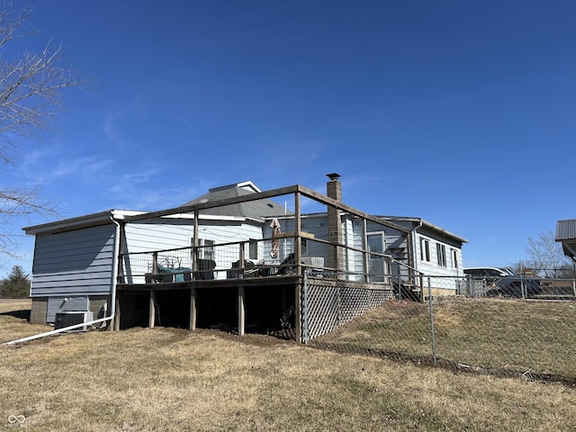 back of property featuring fence, a deck, and a yard