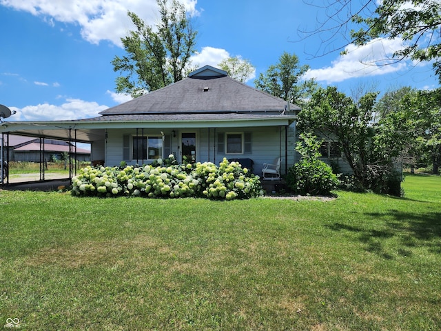 rear view of house with a carport, covered porch, roof with shingles, and a lawn