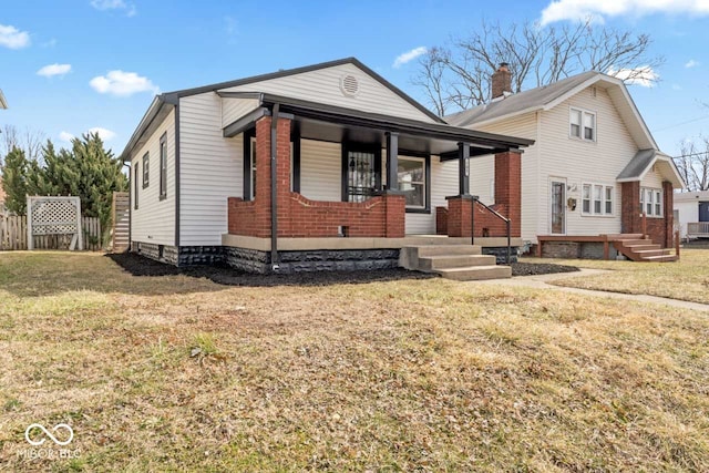 bungalow-style home featuring covered porch, brick siding, a front yard, and fence