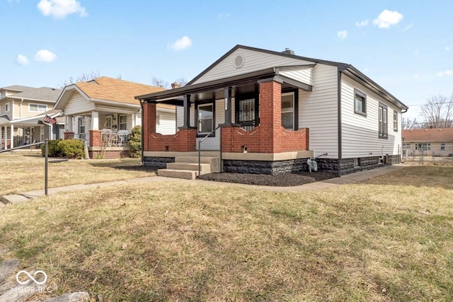 view of front of property with a porch, a front yard, and brick siding