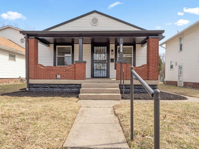 view of front of home with a front lawn, a porch, and brick siding