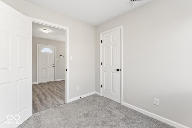 unfurnished room with carpet, visible vents, and baseboards