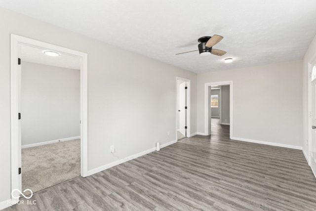 empty room featuring wood finished floors, a ceiling fan, and baseboards