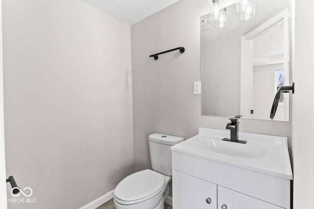 half bath with vanity, toilet, and baseboards