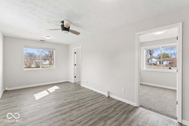 unfurnished bedroom with a textured ceiling, multiple windows, and wood finished floors