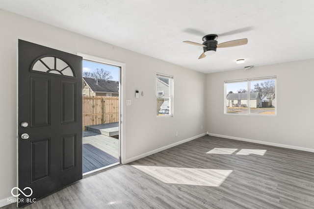 doorway to outside with ceiling fan, visible vents, baseboards, and wood finished floors