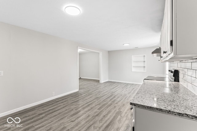 interior space with light wood-type flooring, baseboards, and a tile fireplace