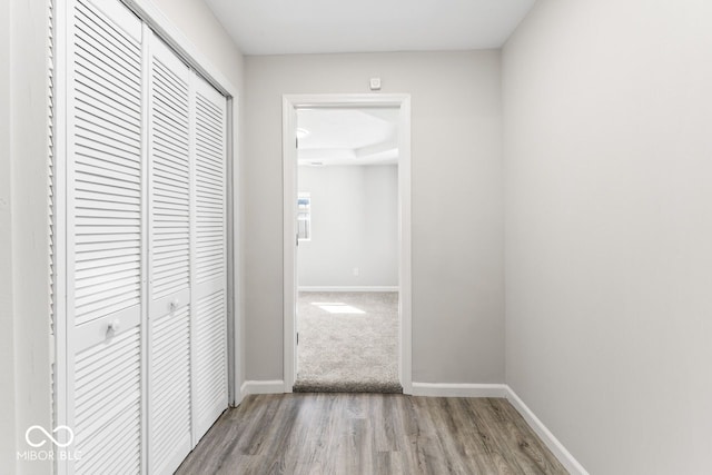 corridor featuring baseboards and wood finished floors