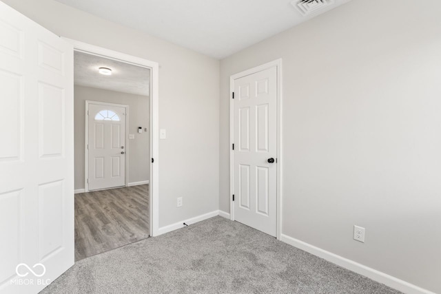 foyer with baseboards, visible vents, and carpet flooring