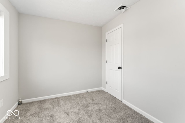 empty room featuring carpet floors, visible vents, and baseboards