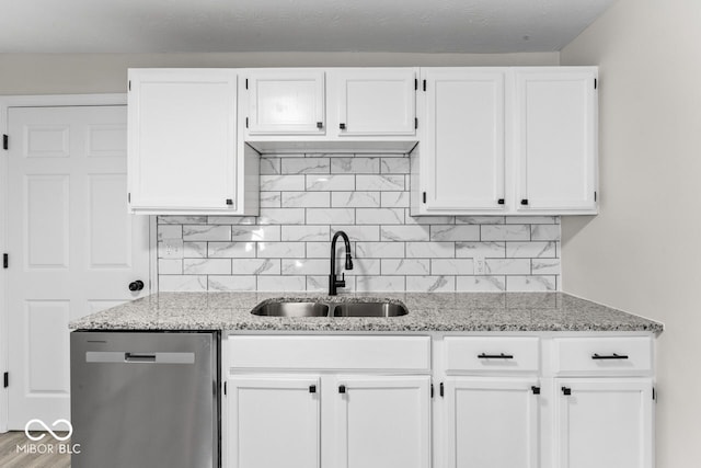 kitchen featuring decorative backsplash, white cabinetry, a sink, and stainless steel dishwasher