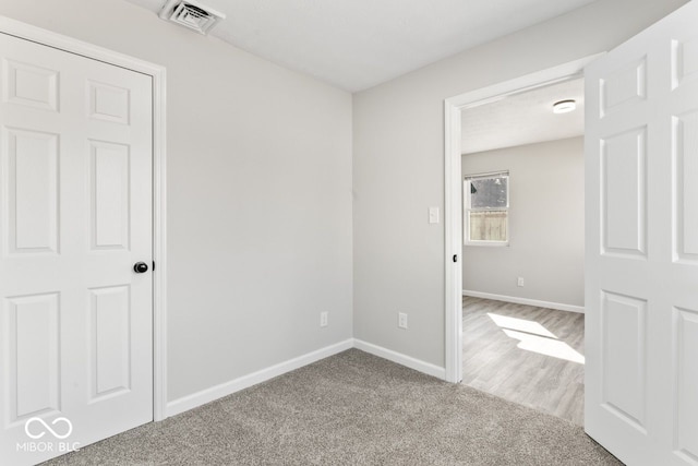 empty room featuring carpet flooring, visible vents, and baseboards