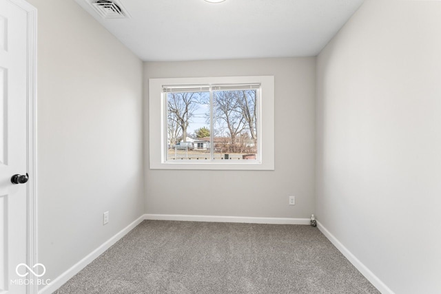 spare room with carpet floors, visible vents, and baseboards