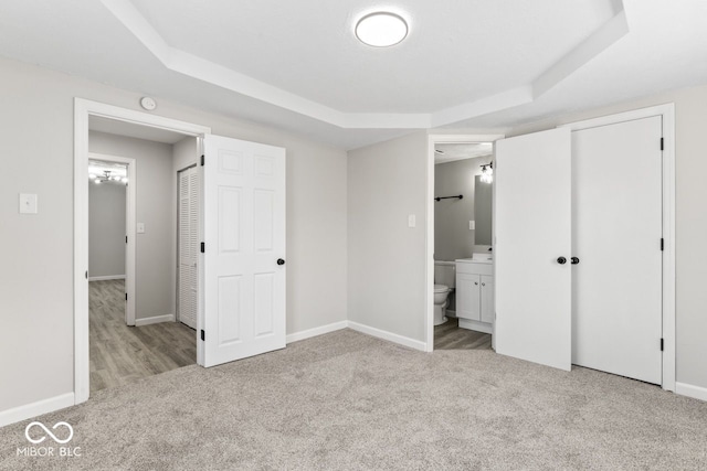 unfurnished bedroom with carpet floors, a raised ceiling, and baseboards