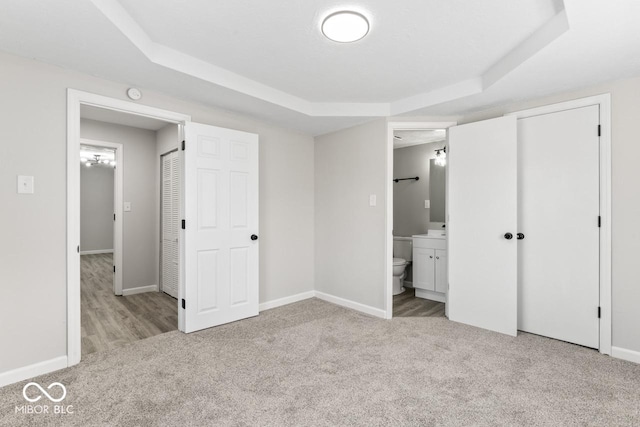 unfurnished bedroom with carpet, baseboards, and a raised ceiling