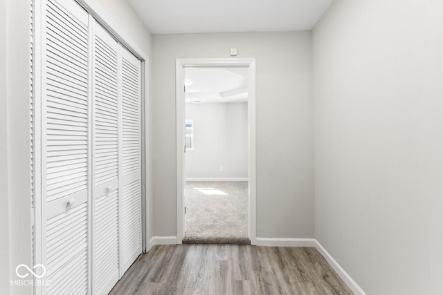 corridor with baseboards and wood finished floors