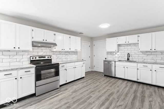 kitchen featuring light wood-style flooring, under cabinet range hood, stainless steel appliances, a sink, and white cabinetry