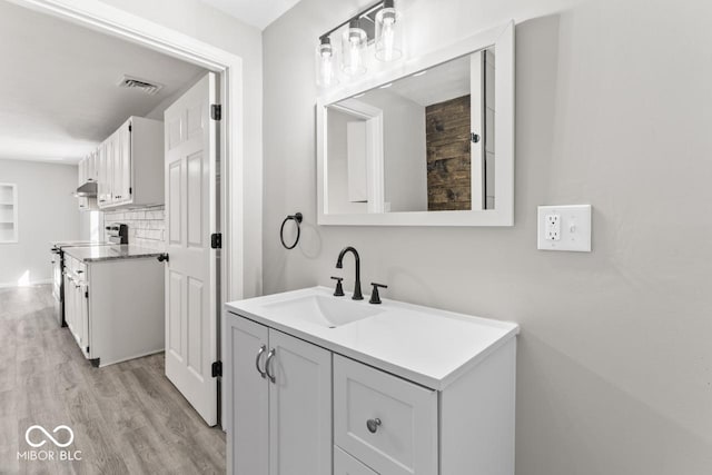 bathroom with visible vents, decorative backsplash, wood finished floors, and vanity