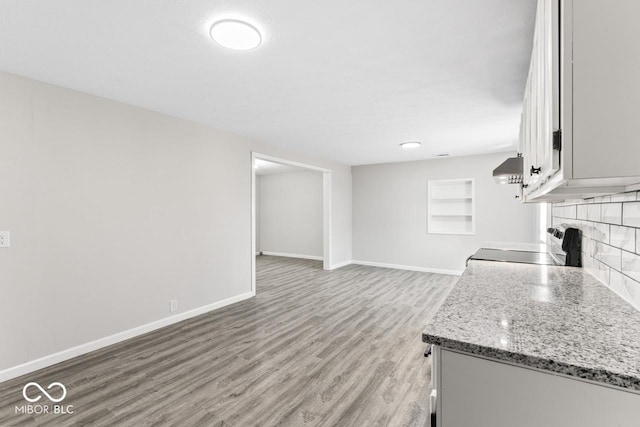 kitchen featuring decorative backsplash, light wood-style floors, open floor plan, range with electric cooktop, and baseboards