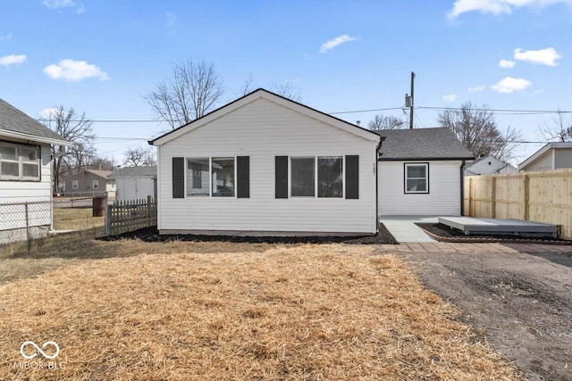 back of house with roof with shingles, fence, a patio, and a yard