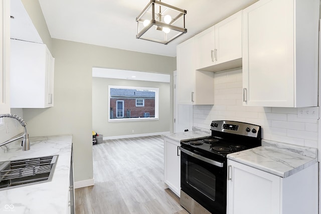 kitchen featuring tasteful backsplash, white cabinetry, a sink, light stone countertops, and stainless steel electric range