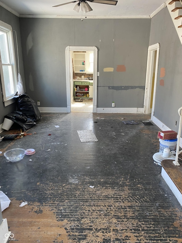 unfurnished living room with baseboards, ceiling fan, and crown molding