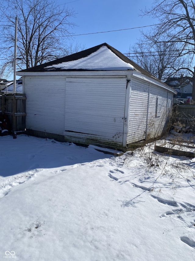 snow covered garage with a detached garage and fence