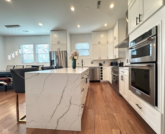 1818 N Cornell Ave, Indianapolis, IN 46202 - kitchen featuring stainless steel appliances, a center island, light stone countertops, a breakfast bar area, and dark wood finished floors
