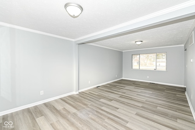 spare room with a textured ceiling, ornamental molding, wood finished floors, and baseboards