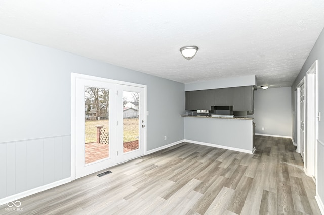 kitchen with baseboards, visible vents, wood finished floors, a peninsula, and a textured ceiling