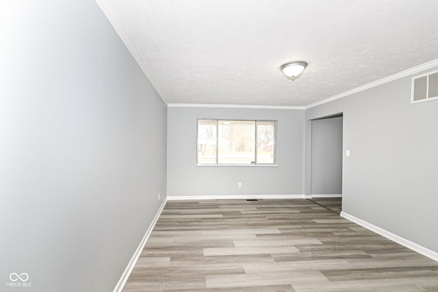 unfurnished room featuring baseboards, visible vents, wood finished floors, and ornamental molding