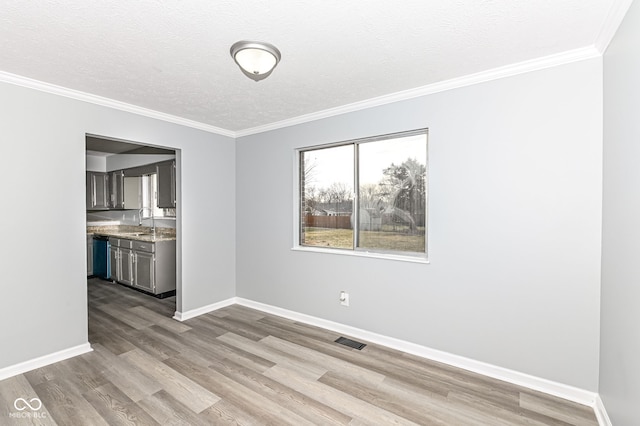 unfurnished dining area featuring a textured ceiling, wood finished floors, visible vents, baseboards, and crown molding