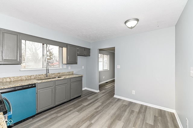 kitchen featuring gray cabinets, light wood-style flooring, a sink, a textured ceiling, and dishwashing machine