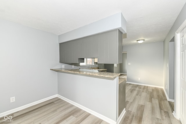 kitchen featuring light wood finished floors, baseboards, and gray cabinets