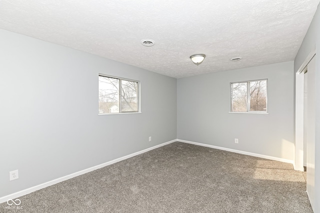 carpeted spare room with baseboards, visible vents, and a textured ceiling