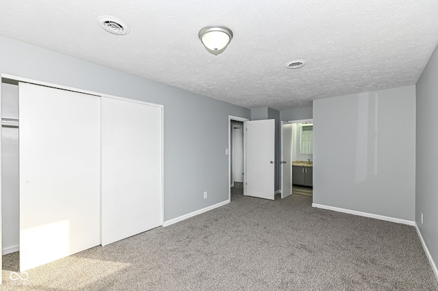 unfurnished bedroom with baseboards, visible vents, carpet, a textured ceiling, and a closet