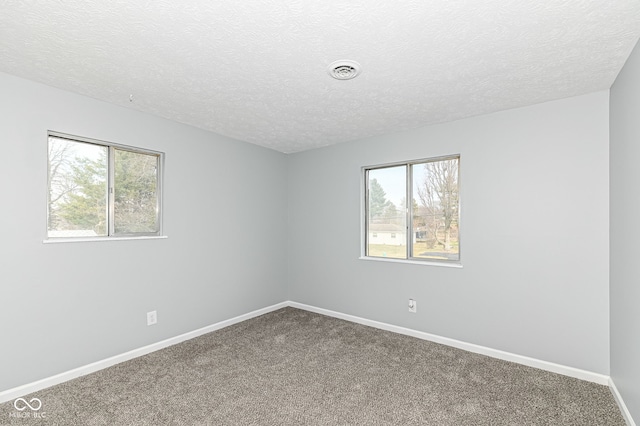 empty room featuring carpet, a healthy amount of sunlight, visible vents, and baseboards