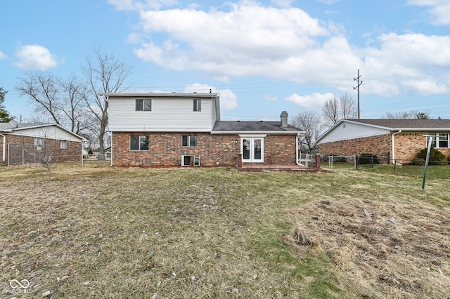 back of property with a lawn, a chimney, fence, french doors, and brick siding