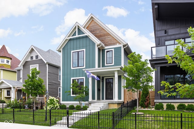 view of front of home featuring board and batten siding, a front yard, a fenced front yard, and a balcony